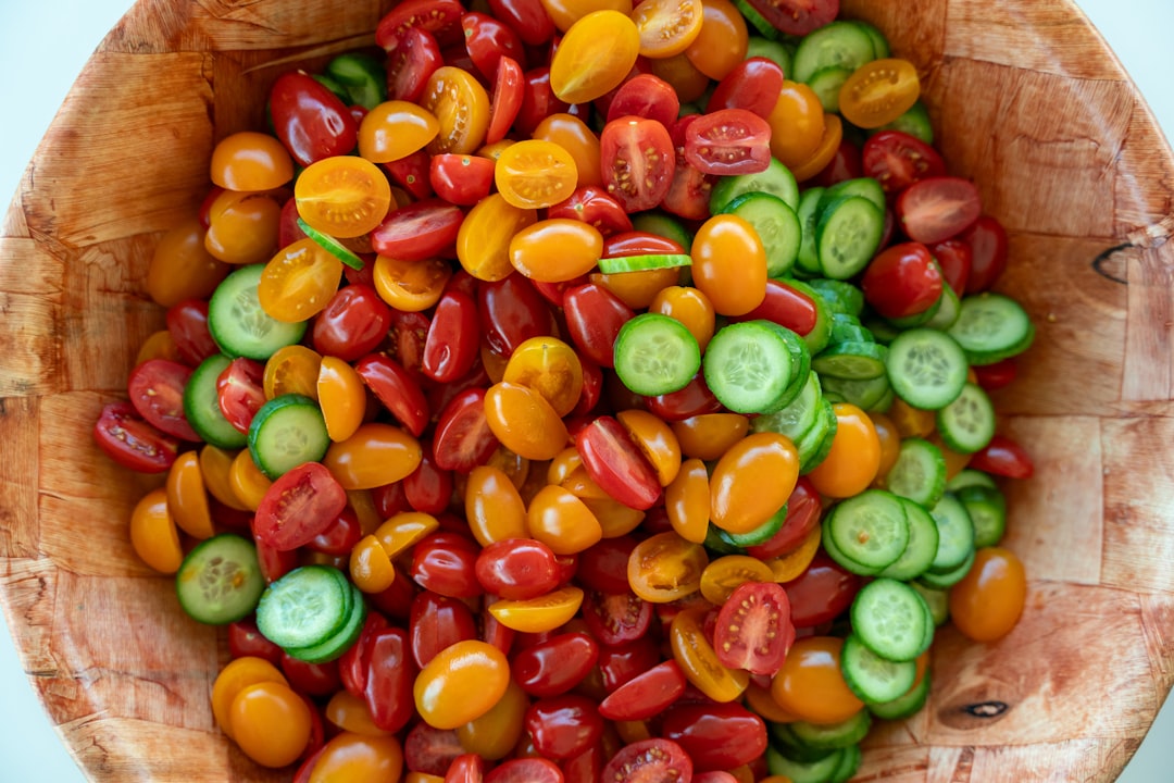 Tomatoes and cucumbers sit in a wooden bowl.