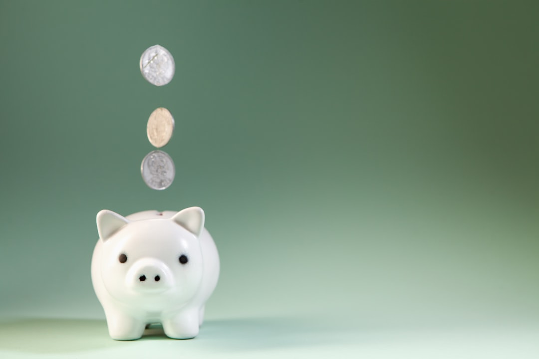 Coins falling into a white piggy bank.