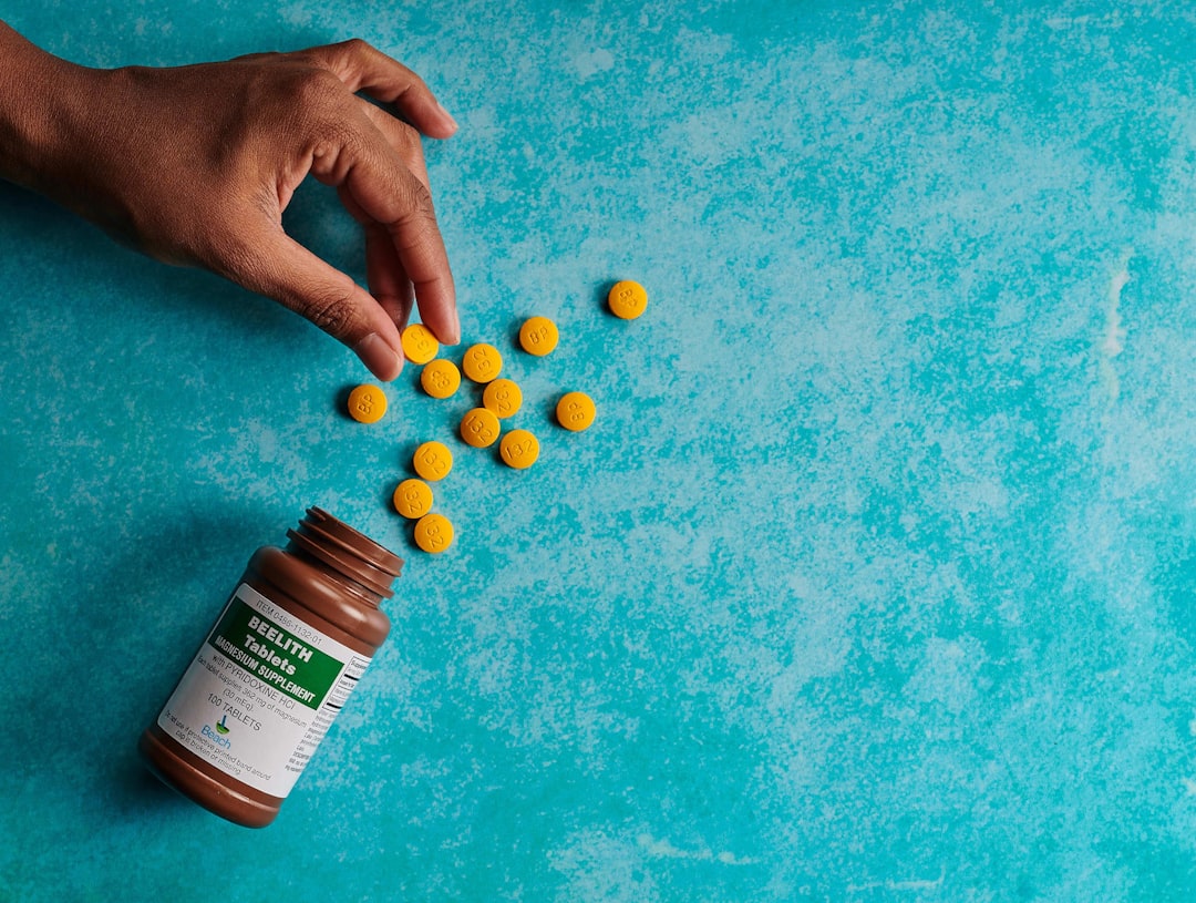 a hand reaching for a bottle of pills on a blue surface